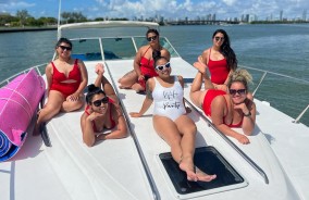 A private boat rental in Miami with a group of young women lounging on the bow